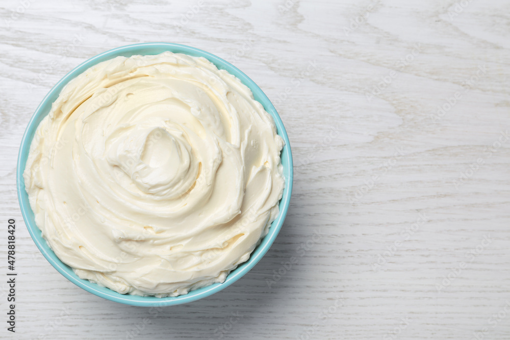 Bowl of tasty cream cheese on white wooden table, top view. Space for text Bowl of tasty cream cheese on white wooden table, top view. Space for text