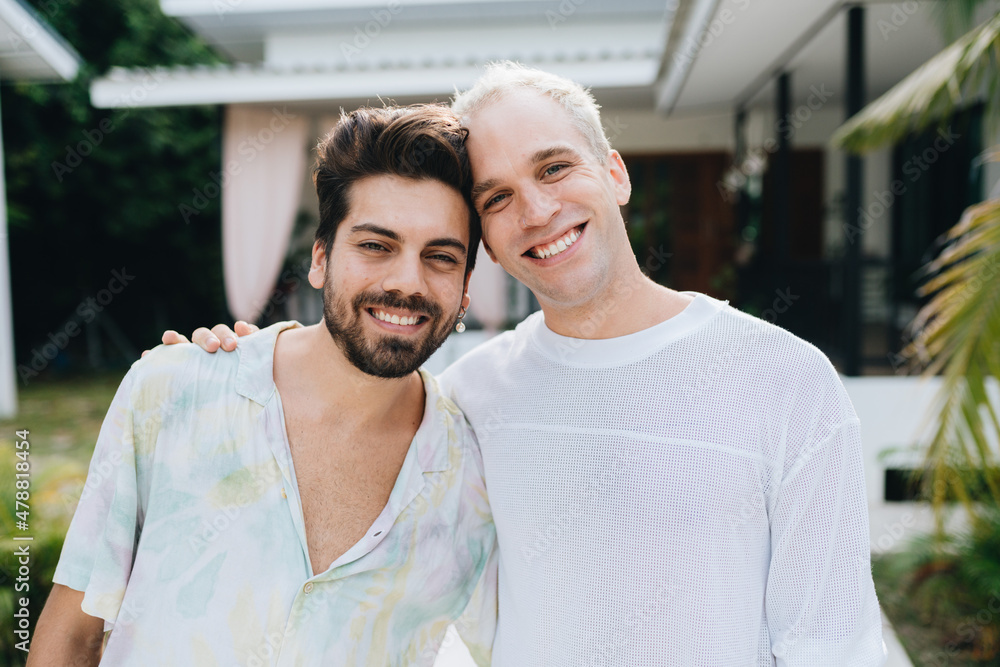 Gay hugging couple standing in front of their house Gay hugging couple standing in front of their house
