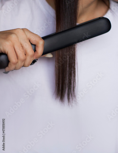 the girl straightens her hair with a curling iron