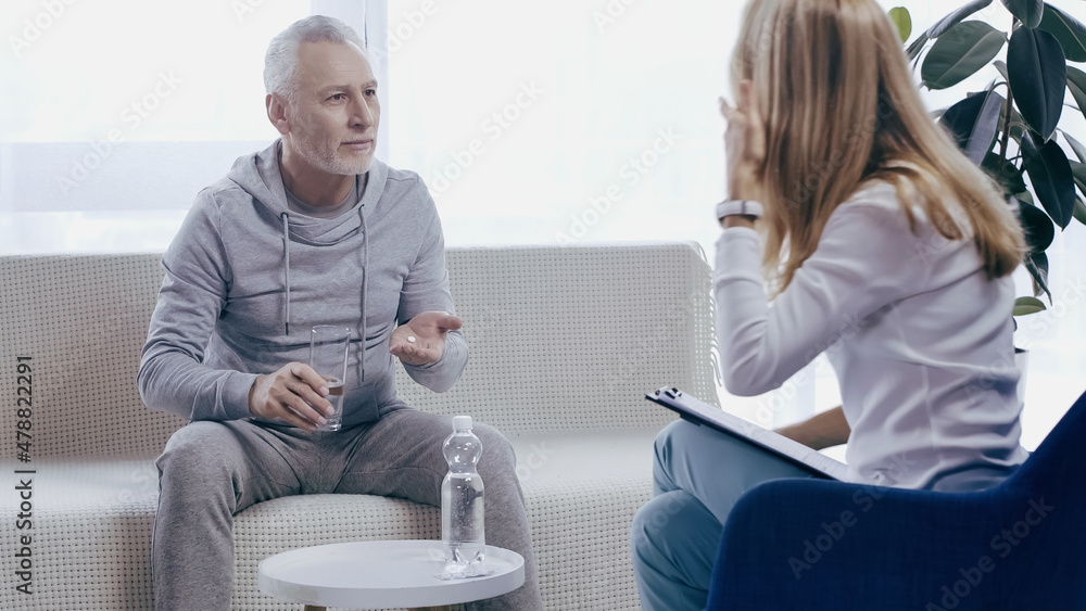 middle aged man in sportswear taking pill near near psychotherapist middle aged man in sportswear taking pill near near psychotherapist