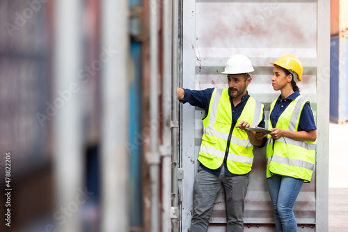 Hispanic Man worker and woman Supervisor dock cargo checking and control loading Containers box at container yard port of import and export goods. Unity and teamwork concept