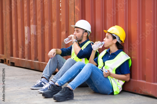 Tired hispanic male and female container worker in hardhat and uniform resting at container yard port of import and export. © NVB Stocker