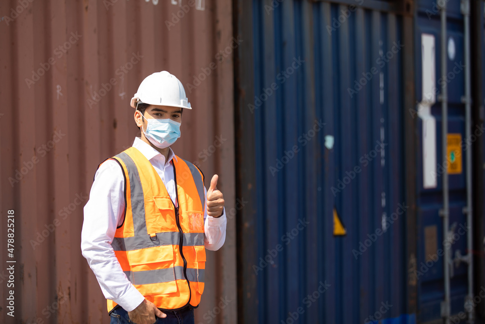 professional engineer man wearing protection face mask during coronavirus and flu outbreak and wearing safety hardhat helmet at container yard or cargo warehouse professional engineer man wearing protection face mask during coronavirus and flu outbreak and wearing safety hardhat helmet at container yard or cargo warehouse
