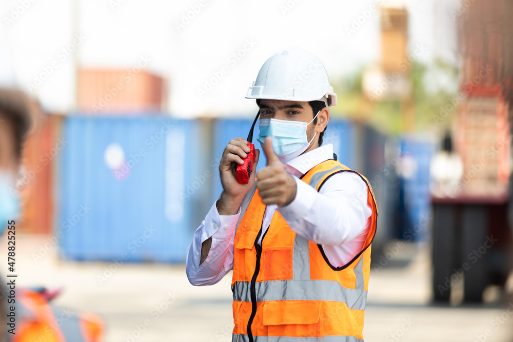 professional engineer man wearing protection face mask during coronavirus and flu outbreak and wearing safety hardhat helmet at container yard or cargo warehouse professional engineer man wearing protection face mask during coronavirus and flu outbreak and wearing safety hardhat helmet at container yard or cargo warehouse