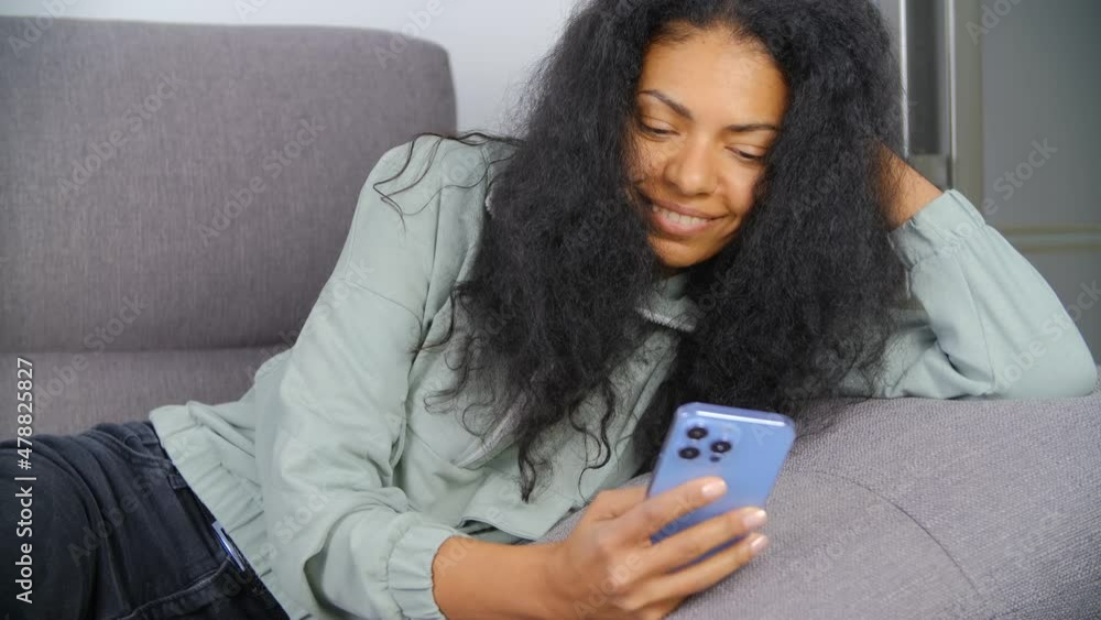 Happy black woman using dating app on mobile phone. Relaxed African female communicating online on social media app. Cheerful person browsing internet on smartphone. BIPOC person lifestyle video Happy black woman using dating app on mobile phone. Relaxed African female communicating online on social media app. Cheerful person browsing internet on smartphone. BIPOC person lifestyle video