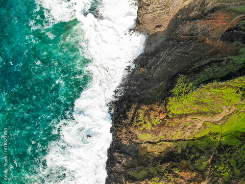 Hiking along the Kalalau Trail in Kauai, Hawaii. The famous Na Pali Coast is full of cliffs, ridges, and waterfalls.