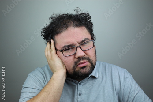 Teeth problem. Man suffering from strong tooth pain, gray studio background. Upset middle-aged man rubbing his cheek, got teeth inflammation.