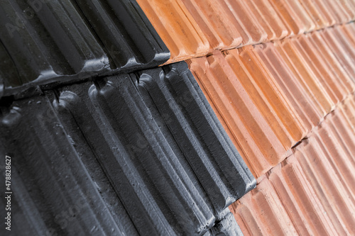 Close up photography of roof before and after it was painted. Half job done. Black and orange tiles. New and old. Roof top reconstruction.