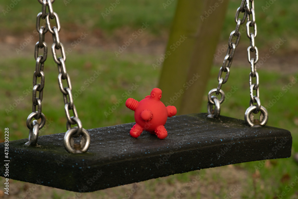 Coronavirus spread among children - rubber toy looking like covid19 cell on a swing at the playground at the kindergarten.