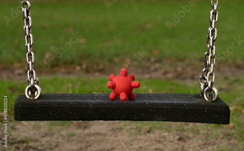 Obraz na płótnie Coronavirus spread among children - rubber toy looking like covid19 cell on a swing at the playground at school. w salonie