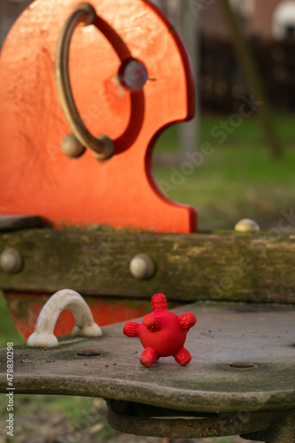 Obraz na płótnie Covid19 spreading among children at school. Red rubber corona ball on a wooden swing at the kindergarten. w salonie