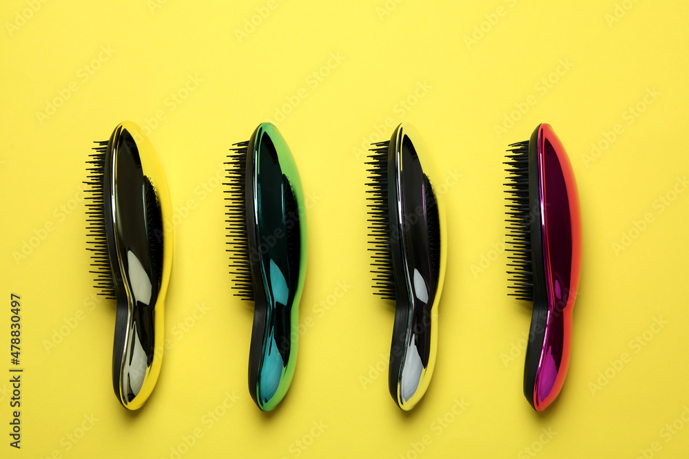Colored plastic hair brushes on yellow background Colored plastic hair brushes on yellow background