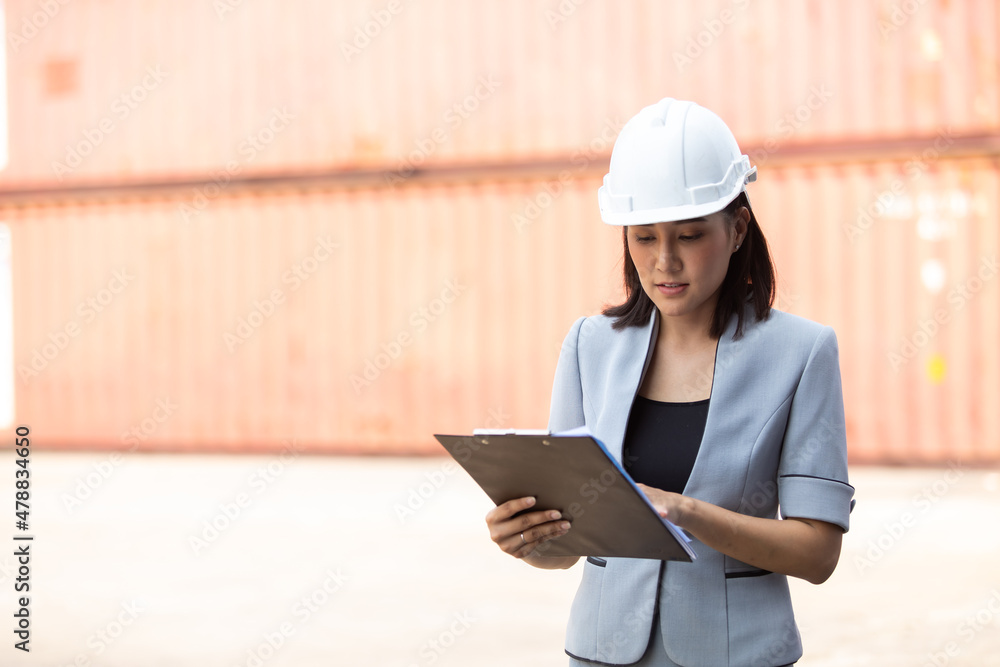 Asian business Women manager control loading Containers box from Cargo at container yard. Import and Export concept. Marine, carrier and logistic insurance Asian business Women manager control loading Containers box from Cargo at container yard. Import and Export concept. Marine, carrier and logistic insurance