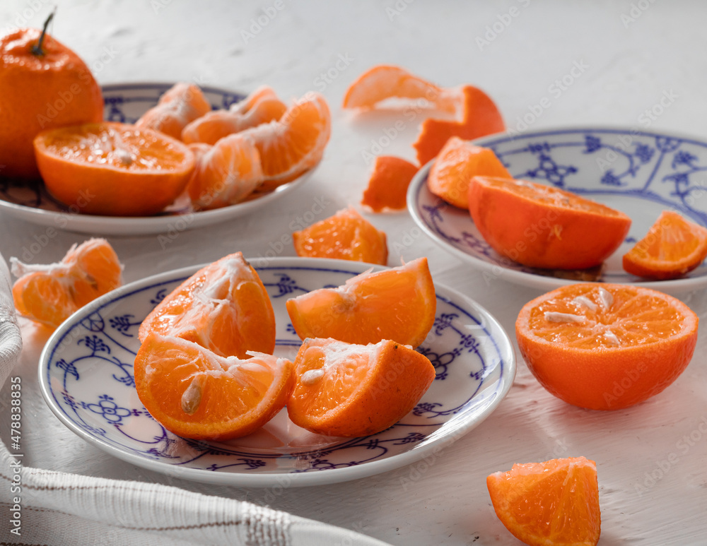 Fresh mandarin oranges on a white blue ceramic plate. Side view. Fresh mandarin oranges on a white blue ceramic plate. Side view.