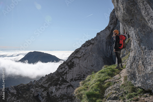 chica en la montaña con una mochila y mar de nubes de fondo