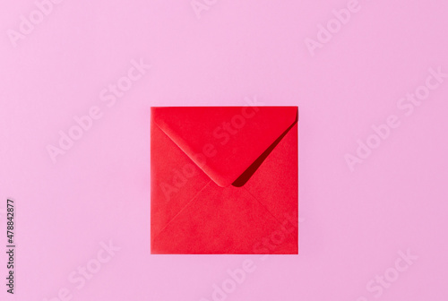 Top view of a red envelope on pastel pink and lavender copy space background. Valentines, love letter, message concept.