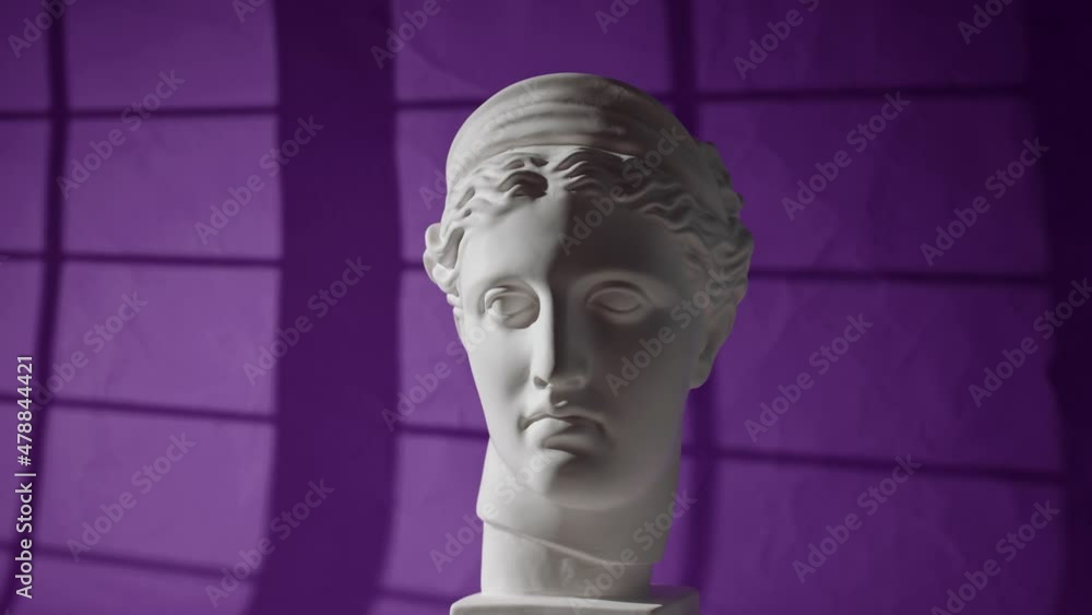 gypsum head of man or woman rotates, light from window falls on purple background. Hard dramatic light on plaster bust. Ancient Greece aesthetic gypsum head of man or woman rotates, light from window falls on purple background. Hard dramatic light on plaster bust. Ancient Greece aesthetic