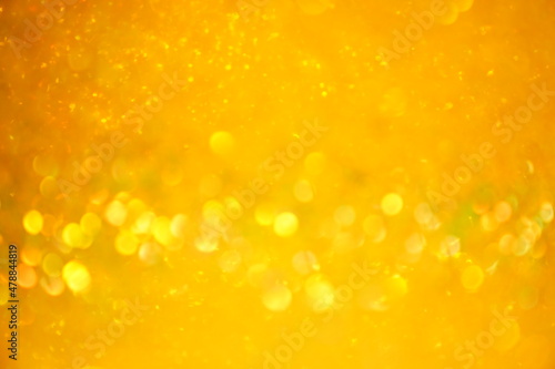 The blurred texture of the golden shine. Background with gold glitter or yellow sequins. Seamless texture with yellow gold sequins. Flickering background. High quality photo