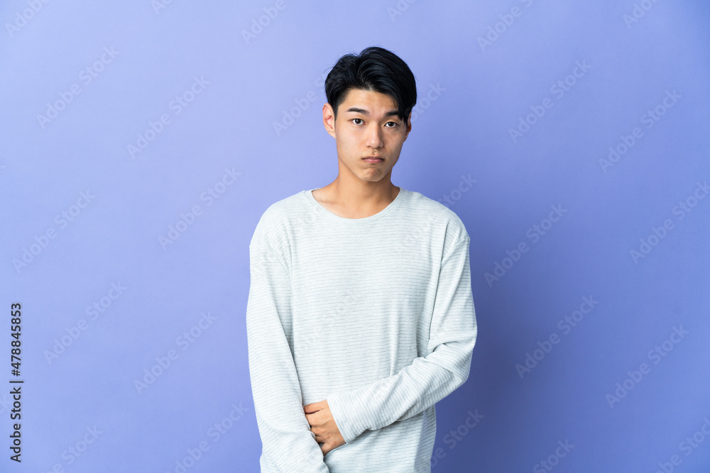 Young Chinese man isolated on purple background with sad expression Young Chinese man isolated on purple background with sad expression