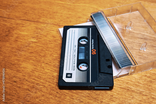 Audio cassette and case on a wooden table. Vintage compact cassette tape for magnetic recording