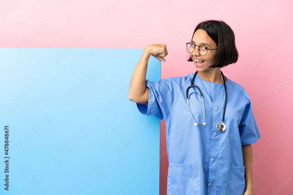 Young mixed race surgeon woman with a big banner over isolated background doing strong gesture Young mixed race surgeon woman with a big banner over isolated background doing strong gesture