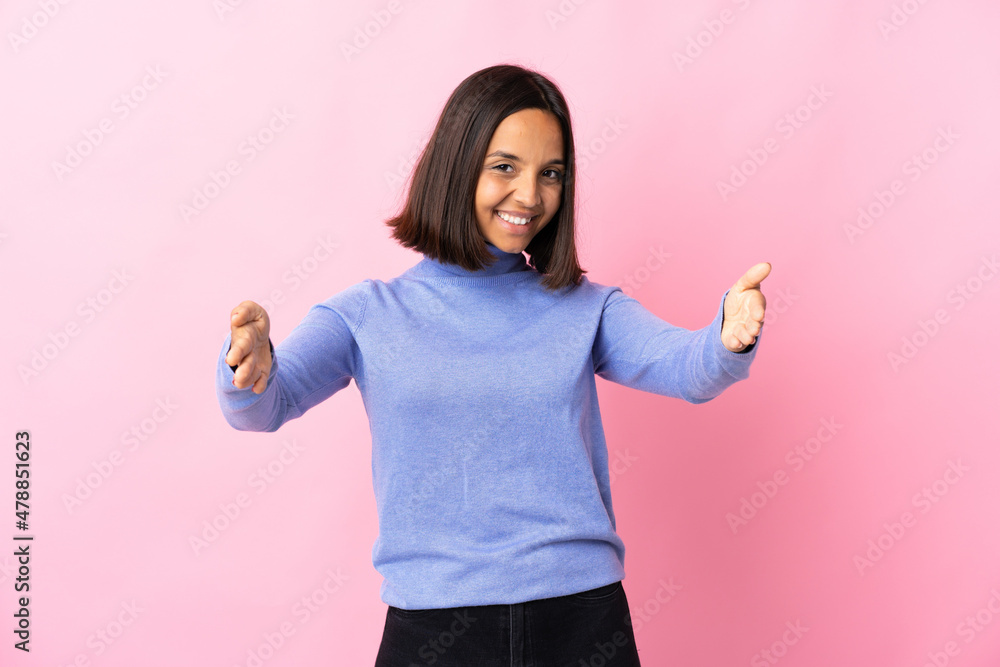 Young latin woman isolated on pink background presenting and inviting to come with hand Young latin woman isolated on pink background presenting and inviting to come with hand