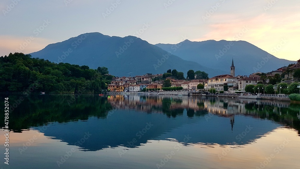 Picturesque little lakeside village Mergozzo at sunset, beautiful reflection in the water. Piedmont, Northern Italy.