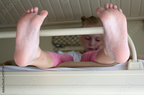 a child girl is sitting in the carriage of a long-distance train on the top shelf in the foreground legs photo