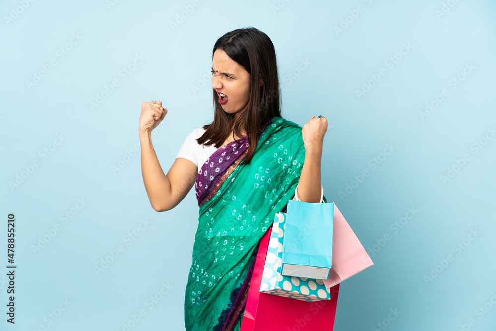 Young Indian woman with shopping bags doing strong gesture Young Indian woman with shopping bags doing strong gesture