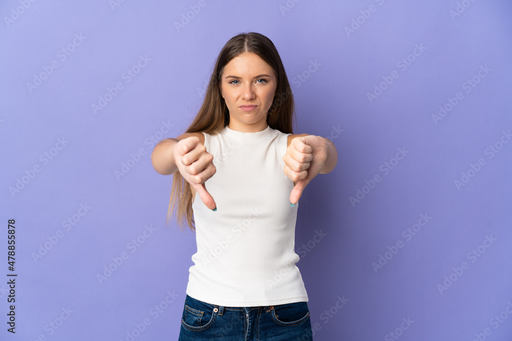 Young Lithuanian woman isolated on purple background showing thumb down with two hands Young Lithuanian woman isolated on purple background showing thumb down with two hands