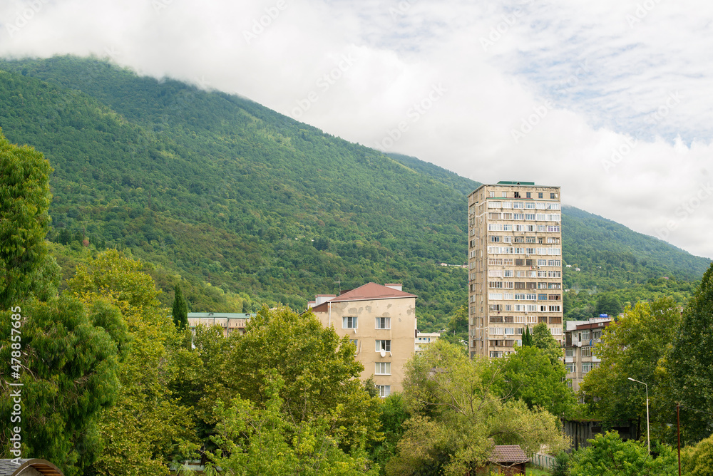 an old multi-storey house on the background of a green mountain in summer