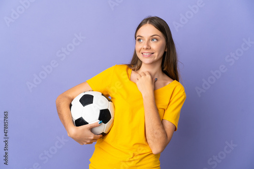 Young Lithuanian football player woman isolated on purple background looking up while smiling © luismolinero