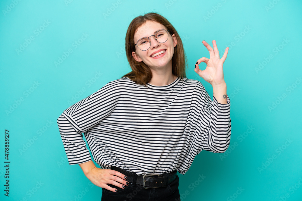 Young English woman isolated on blue background showing ok sign with fingers Young English woman isolated on blue background showing ok sign with fingers