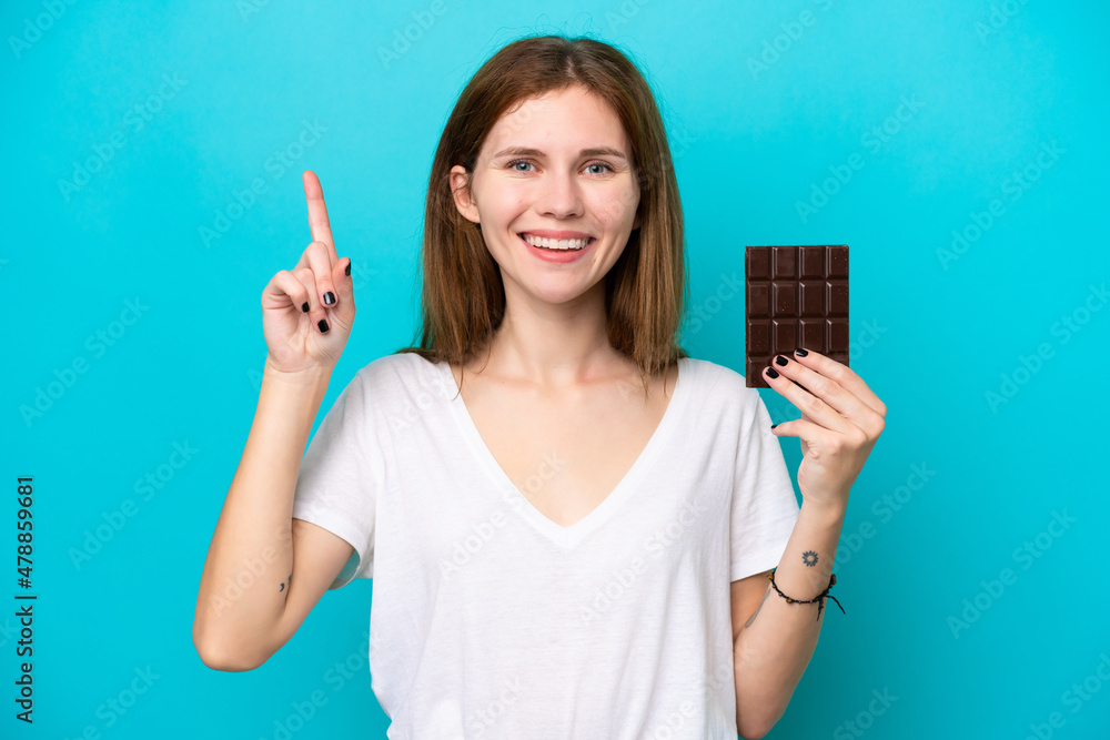 Young English woman with chocolat isolated on blue background pointing up a great idea Young English woman with chocolat isolated on blue background pointing up a great idea