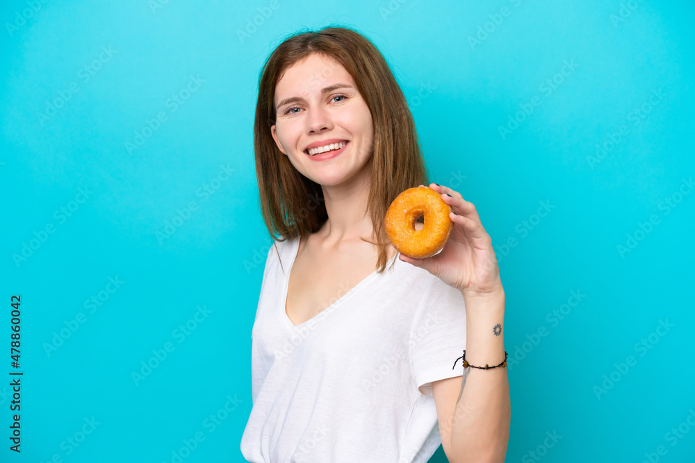 Young English woman holding a donut over isolated blue background smiling a lot Young English woman holding a donut over isolated blue background smiling a lot