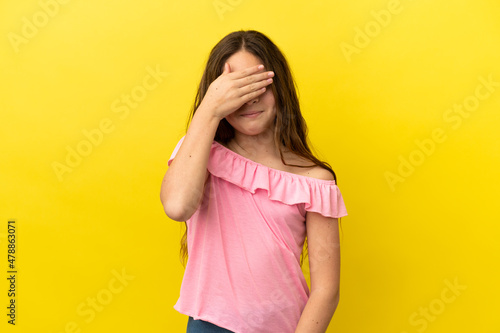 Little caucasian girl isolated on yellow background covering eyes by hands. Do not want to see something © luismolinero