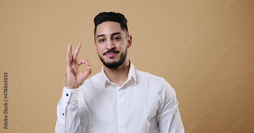 Businessman showing ok gesture with hand over beige background Businessman showing ok gesture with hand over beige background