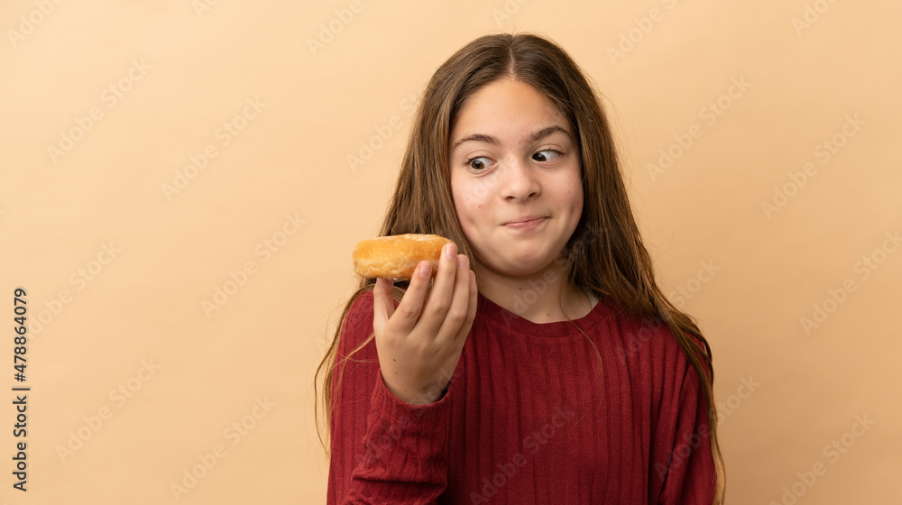 Little caucasian girl isolated on beige background holding donuts Little caucasian girl isolated on beige background holding donuts