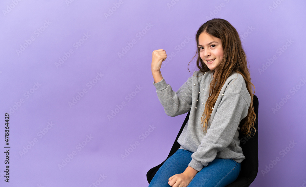 Little caucasian girl sitting on a chair isolated on purple background celebrating a victory