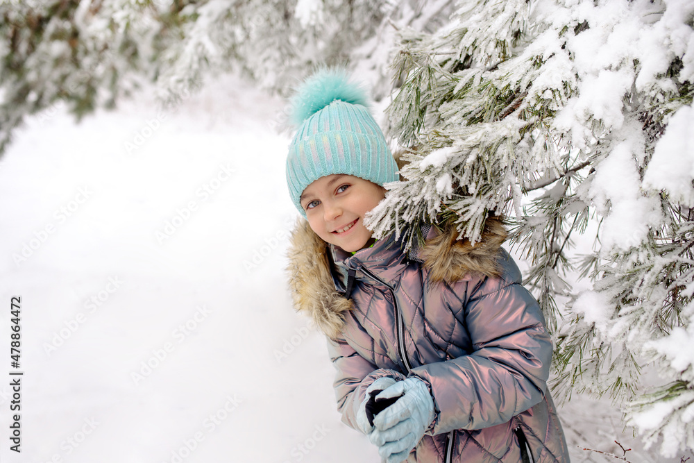A girl in warm winter overalls on a walk in the winter forest: active games, playing snowballs and other activities