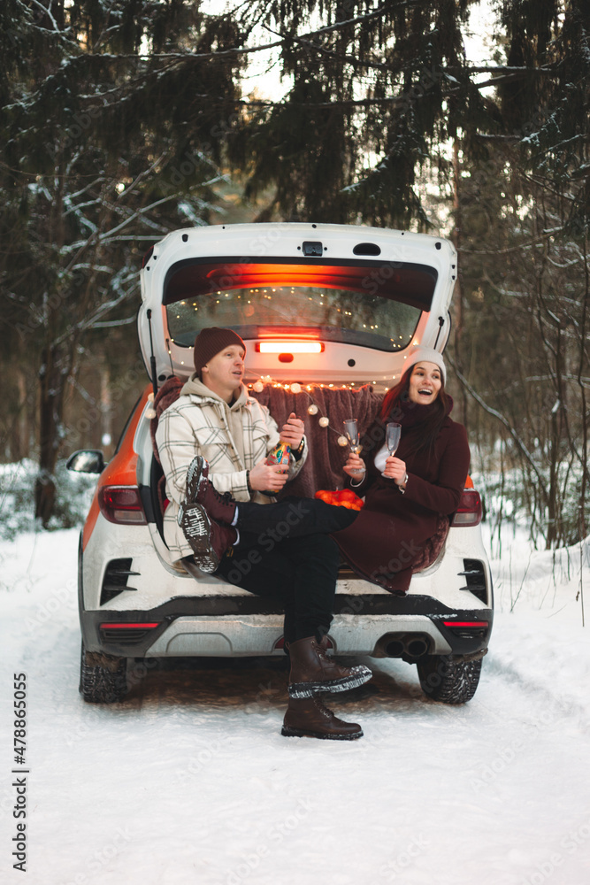 Date in the winter forest. A man and a woman in love drink champagne in