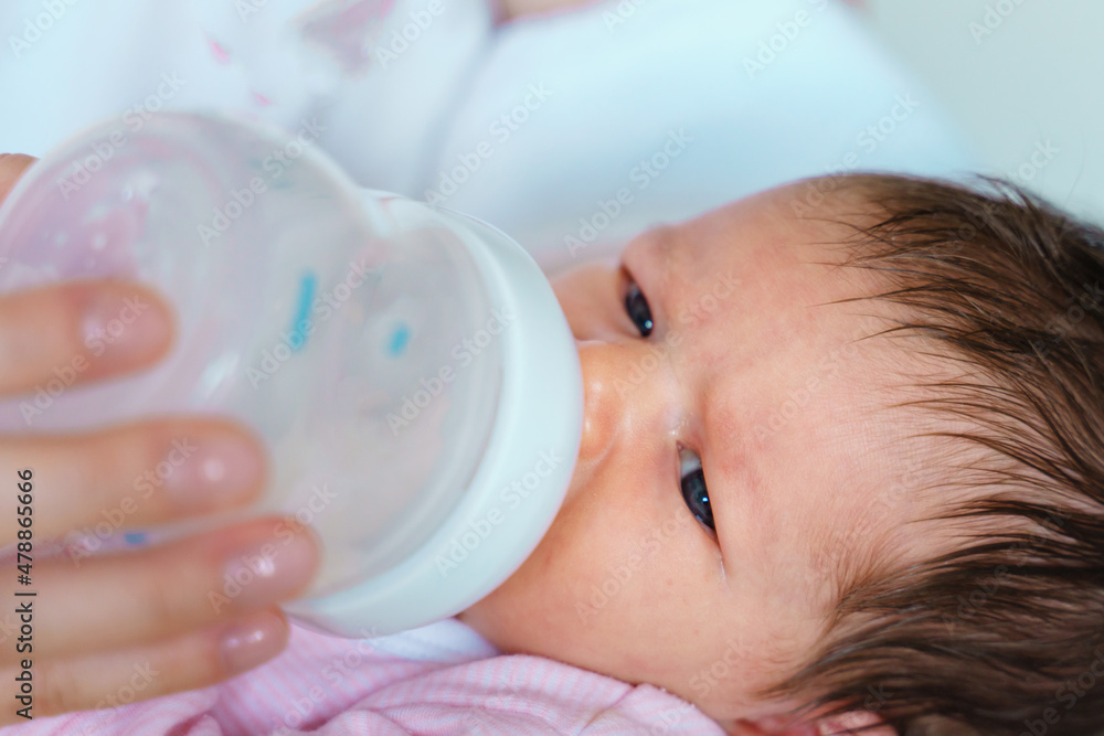 one week old baby lying while bottle feeding artificial formula milk close up one week old baby lying while bottle feeding artificial formula milk close up