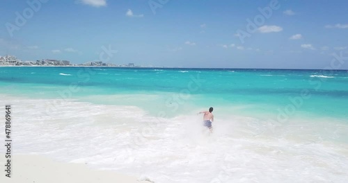 aerial view of a young man running and jumping into the Caribbean Sea, Playa del Carmen, Cancun, Mexico