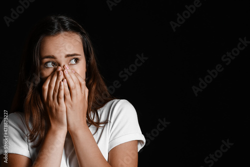 Scared young woman on black...