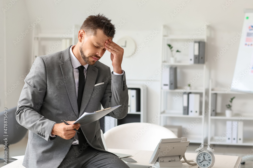 Tired young businessman with document in office Tired young businessman with document in office