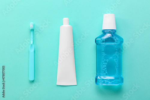 Tube with tooth paste, brush and mouthwash on color background