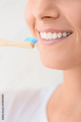 Woman with bamboo tooth brush on light background  closeup
