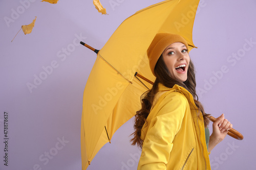 Happy woman in raincoat with opened umbrella on color background photo