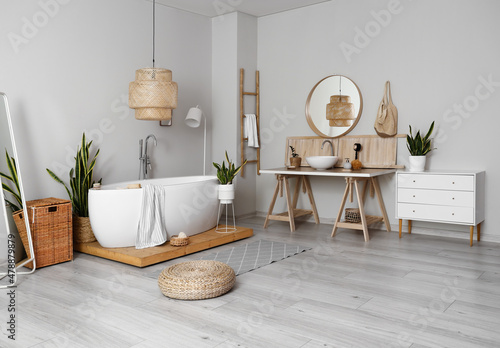Interior of light bathroom with table, sink and houseplants