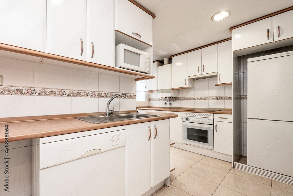 Kitchen with white cabinets and appliances, wooden worktop and stainless steel sink Kitchen with white cabinets and appliances, wooden worktop and stainless steel sink